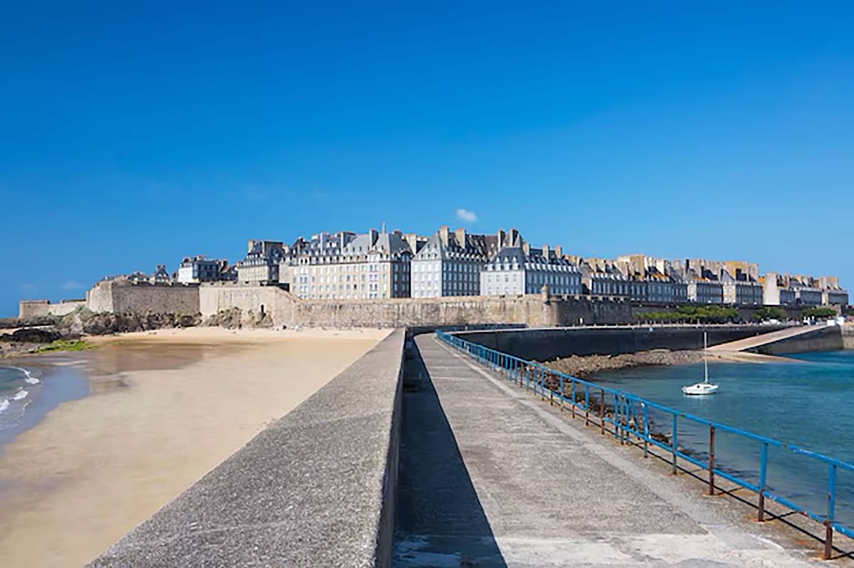Vue d'une plage de sable et d'une fortification en pierre avec des bâtiments historiques près de l'Oceania Saint-Malo